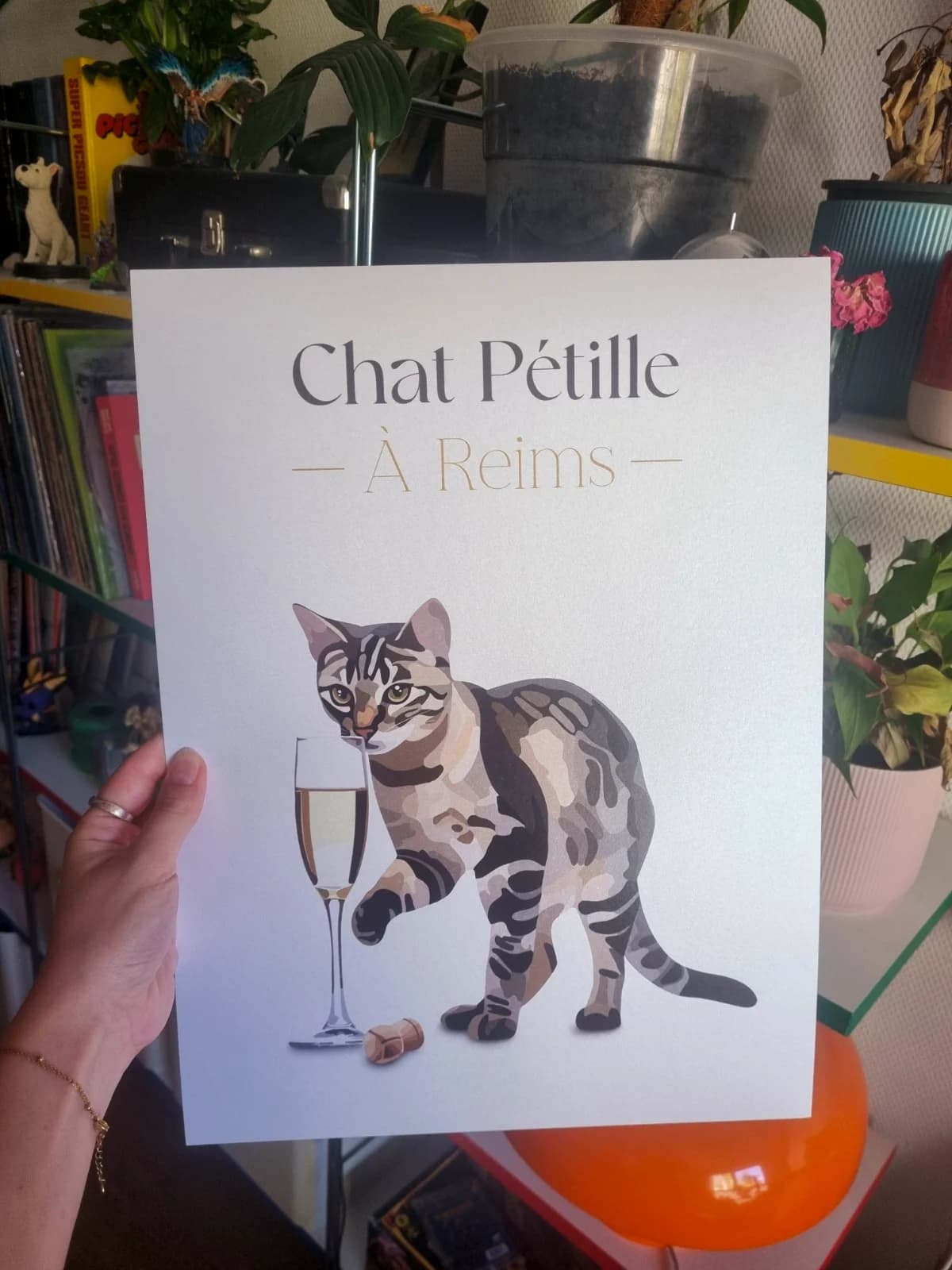 Affiche blanche illustrée d'un chat tigré près d'une flûte et d'un bouchon avec le texte Chat Pétille À Reims.