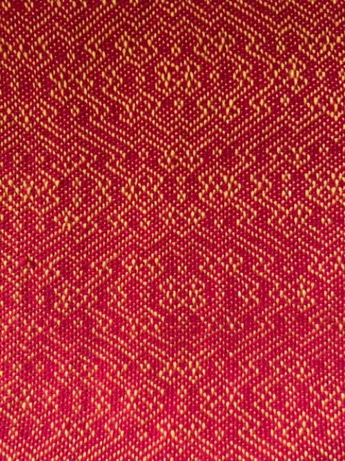 Gros plan sur les motifs géométriques du tissage artisanal rouge et jaune