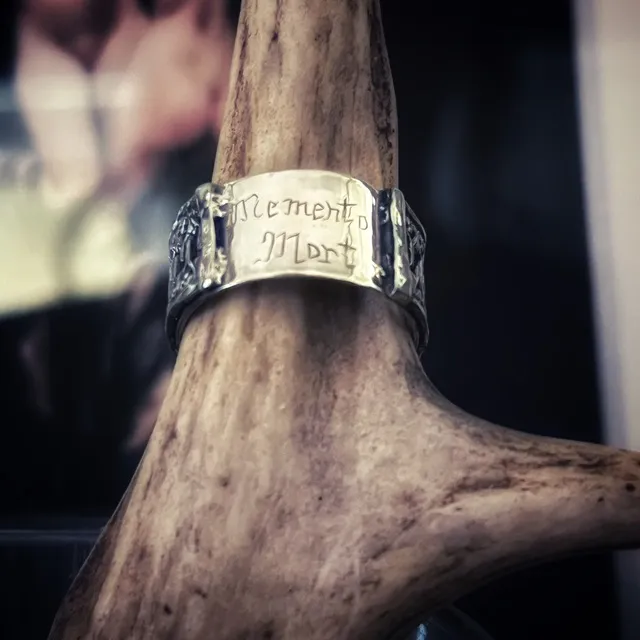 Bague large en argent gravée Memento Mori, présentée sur un bois de cervidé.